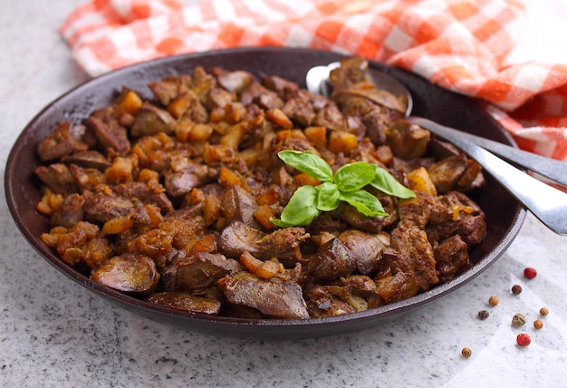 Fried chicken liver in a black plate on a gray marble background