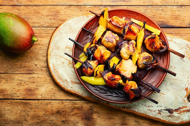 Fried chicken meat on wooden skewers. Shashlik with mango