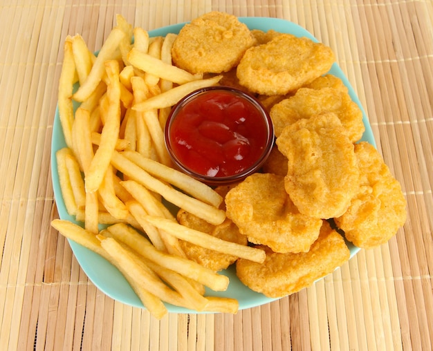 Fried chicken nuggets with french fries and sauce on table in park