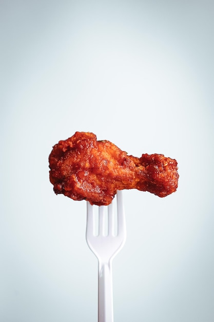 fried chicken on plastic fork with grey background fast food Concept with copy space