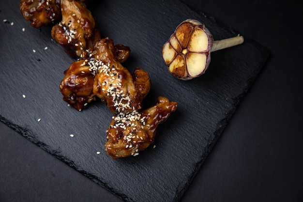 fried chicken wings with sesame seeds and spices on black background