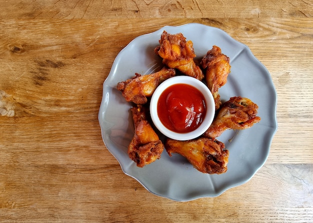 Photo fried chicken wings with tomato sauce on a wooden table