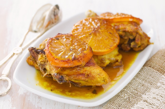 Fried chicken with orange on white dish on wood