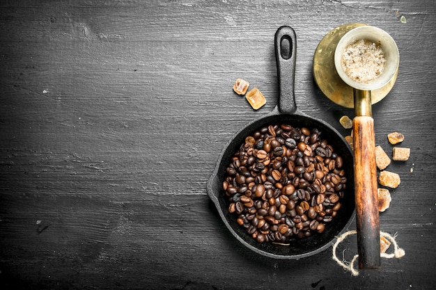 Fried coffee beans in a frying pan. On the black chalkboard.