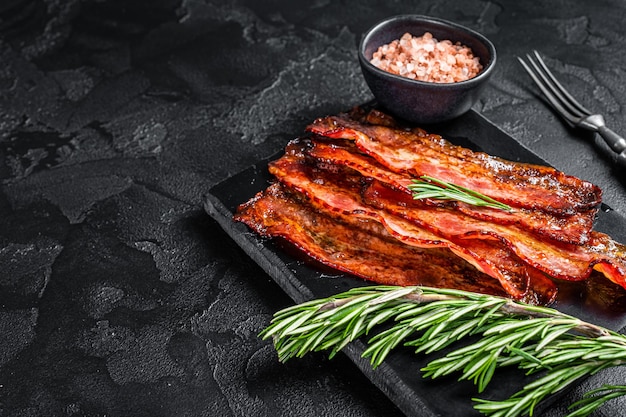 Fried crunchy Streaky Bacon stripes. Black background. Top view. Copy space.