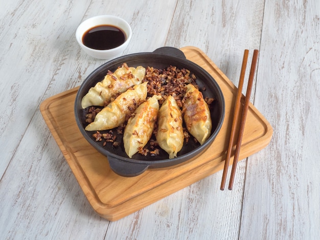 Fried dumplings Gyoza in a frying pan, soy sauce, and chopsticks, top view.