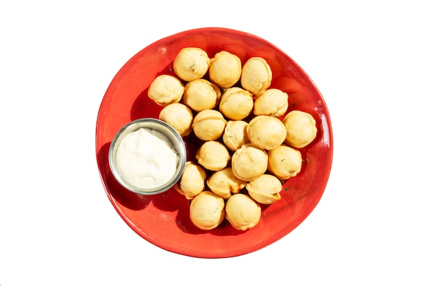 Fried dumplings in a red plate with sour cream sauce