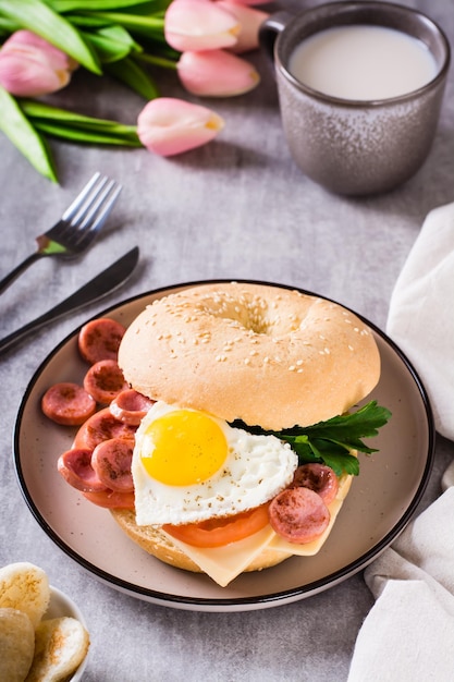 Fried egg heart tomatoes cheese and parsley in a bagel on a plate Romantic breakfast