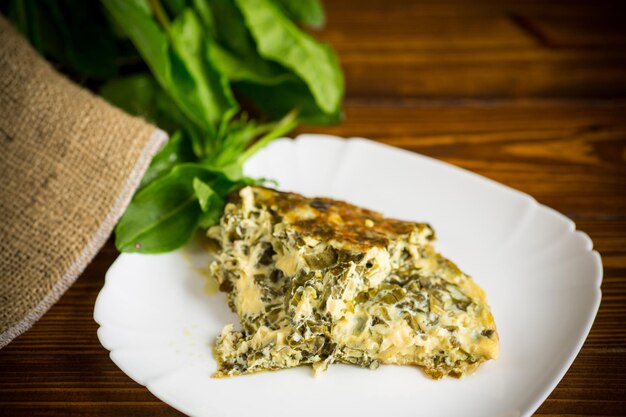 Fried egg omelet with spring sorrel inside on a wooden table