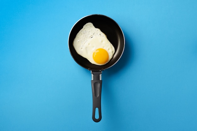 Photo fried egg on pan over blue background