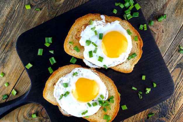 Fried egg sandwich with yolk chili pepper on toasted slice of bread sprinkled with green onions