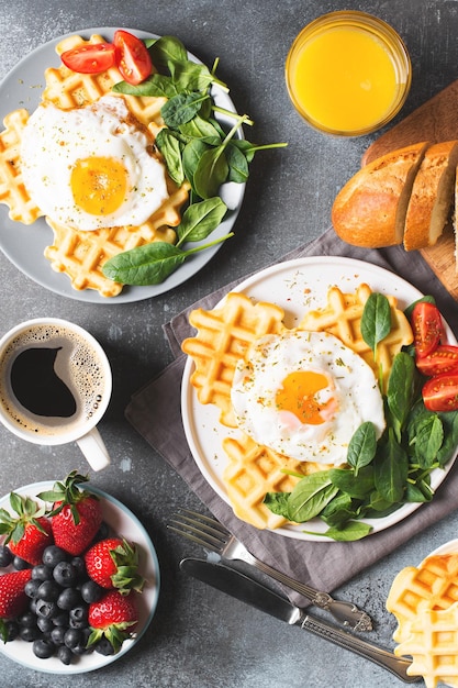 Fried egg spinach waffles and cup of coffee espresso bread baguette on dark background