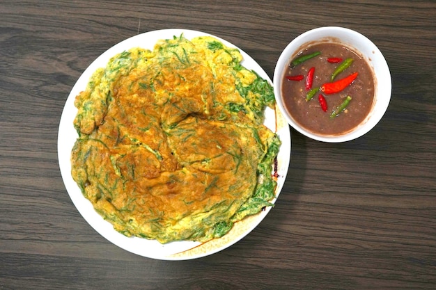 Fried egg with climbing wattle or cha-om omelettes and spicy shrimp paste sauce on wooden background