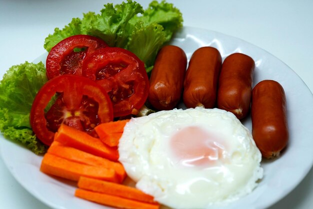 Fried egg with sausages and vegetables on a plate.