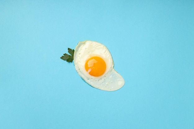 Fried egg with spices on blue background, top view