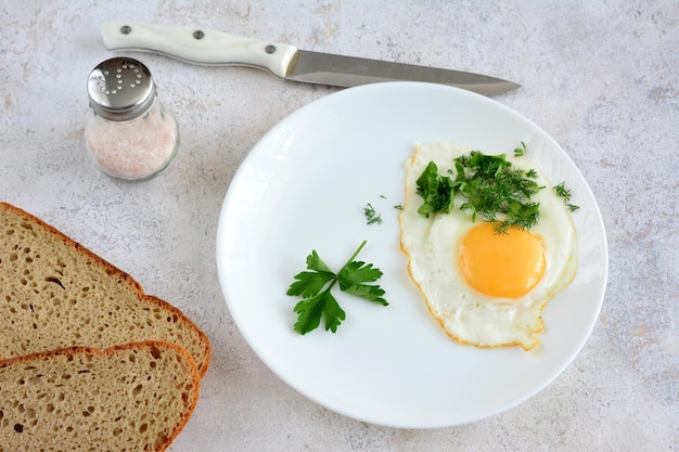 fried egg with yellow yolk and parsley isolated on white plate, close-up