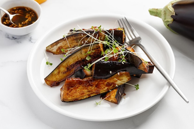 Fried eggplant sticks in the glaze with soy sauce and honey garnished on white plate