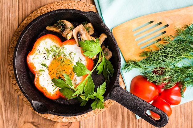 Photo fried eggs in pepper, herbs and mushrooms in the iron pan