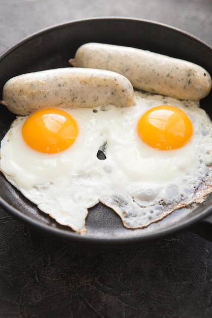 Fried eggs, sausage in iron pan -  Healthy food english breakfast