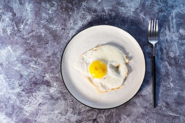 Fried eggs in white plate close-up. View from above.