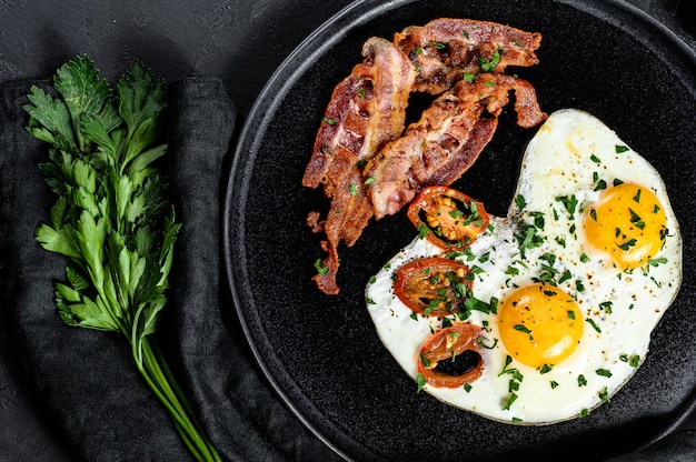 Fried eggs with bacon. Classic Breakfast at the hotel. Black background. Top view