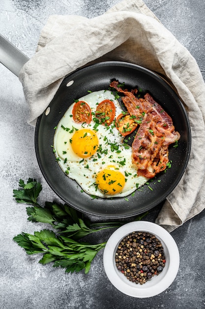 Fried eggs with bacon in a pan. Keto Diet. Keto breakfast. Low carb diet concept. high fat diet. Gray background. Top view