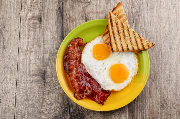 Fried eggs with bacon sausages and greens