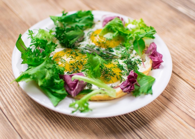 Fried eggs with greens on a plate on a wooden background Healthy breakfast