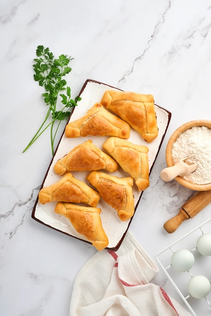 Fried empanadas with cilantro, meat, egg, tomato and chili sauce on white background. Latin American and Chilean independence day concept.