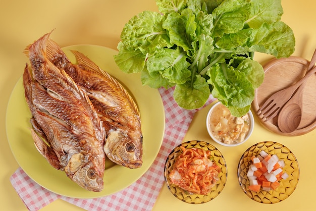 Fried fish on dish served pickled vegetable and fresh green leaves