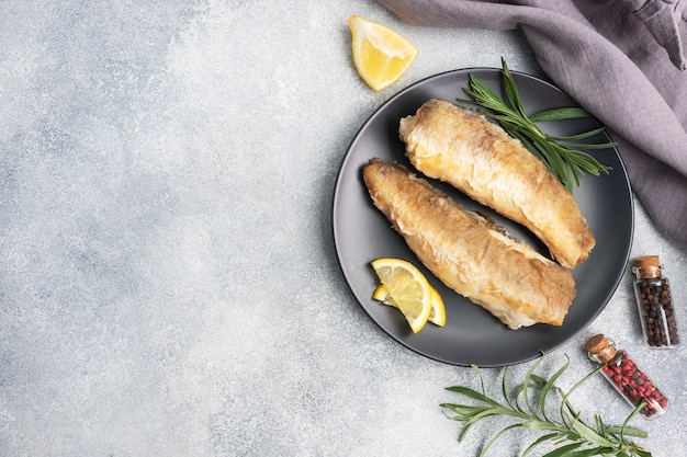 Fried fish hake Pollock and slices of fresh lemon.