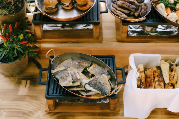 Fried fish in a skillet in the kitchen with focaccia bread and hot meals for a banquet