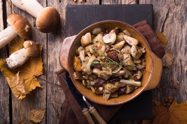 Fried forest mushrooms, boletus, onions. Rustic dish in a frying pan, vegetarian autumn food on top of view