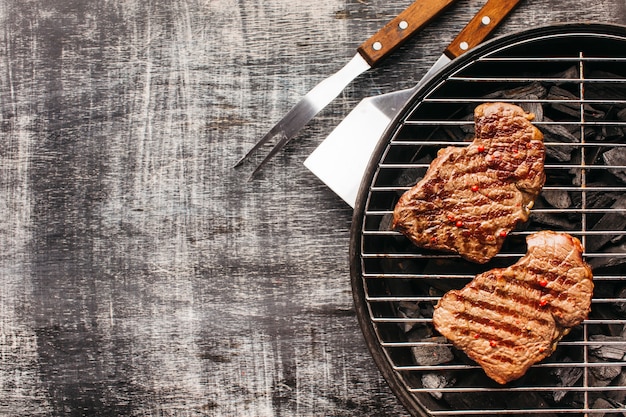 Fried garnish steak on barbecue grill on old backdrop