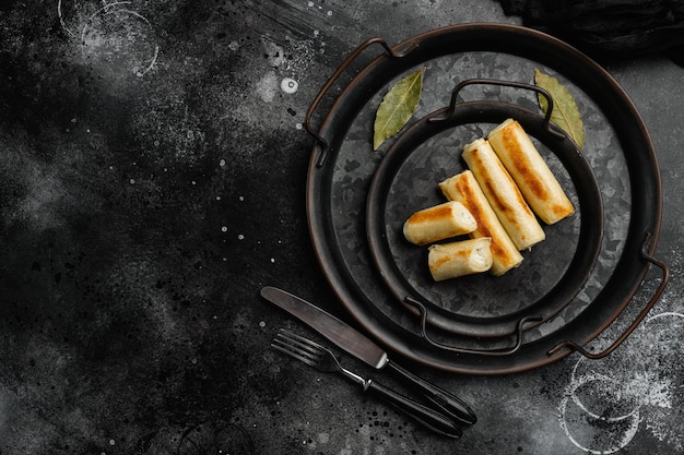 Fried georgian crepes stuffed with suluguni on black dark stone table background top view flat lay with copy space for text