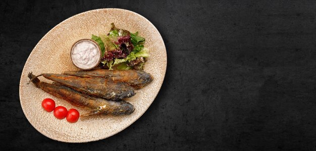 Photo fried goby fish in a plate on a dark concrete background