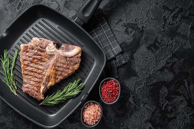 Fried on a grill skillet t bone porterhouse beef meat Steak Black background Top view Copy space