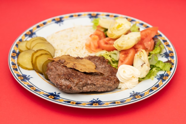 Fried ground meat with fresh salad and boiled rice on white plate