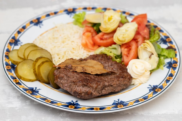 Fried ground meat with fresh salad and boiled rice on white plate