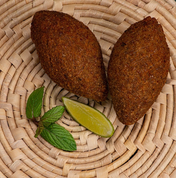 Fried kibbeh on straw mat with mint and lemon