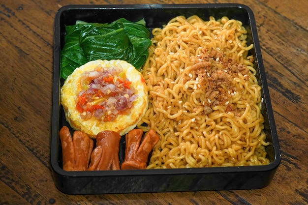 fried noodle bento box set with egg, sausage and vegetables