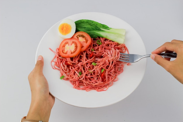 Fried noodles served with fried eggs and vegetables on a plate