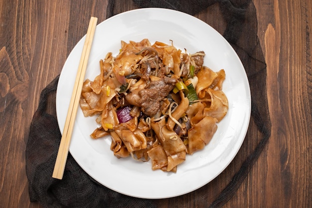 Fried noodles with vegetables and beef in white dish