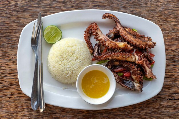 Fried octopus tentacles with white rice on a plate close up