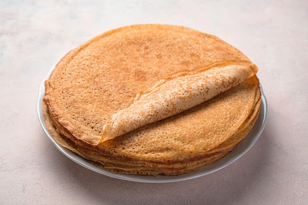 Fried pancakes in a stack on a light background. Traditional Russian blini. Pancake day. Side view, close-up.