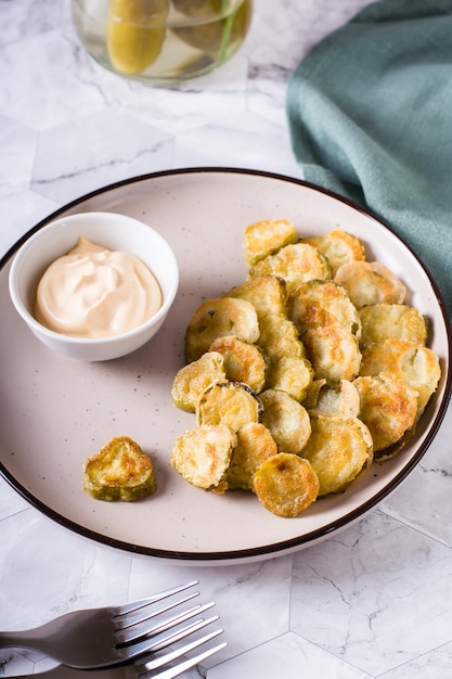 Fried pickles appetizer and sauce in a bowl on a plate Homemade snack Vertical view