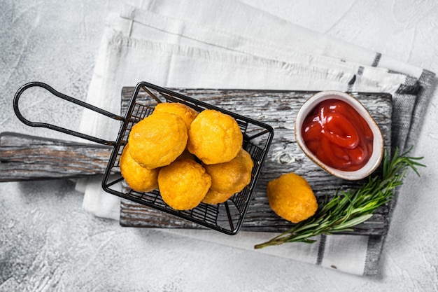 Fried potato cheese balls croquettes with tomato ketchup served in a basket White background Top view