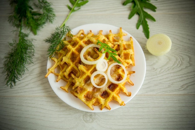 Fried potato cheese vegetable waffles with bacon and onions in a plate on a wooden table