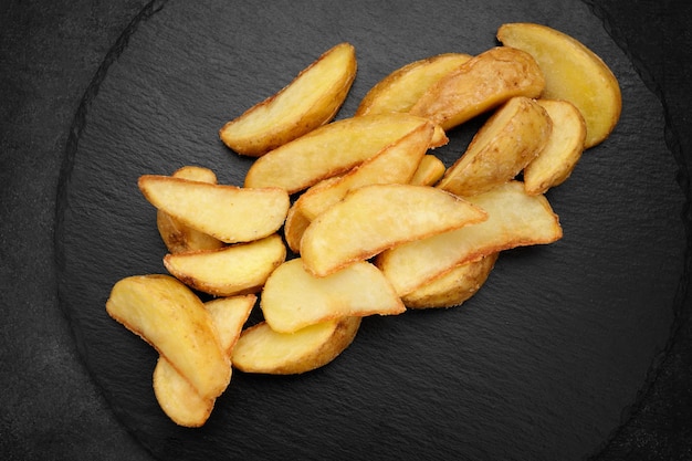 Fried potato wedges on black slate Dark concrete