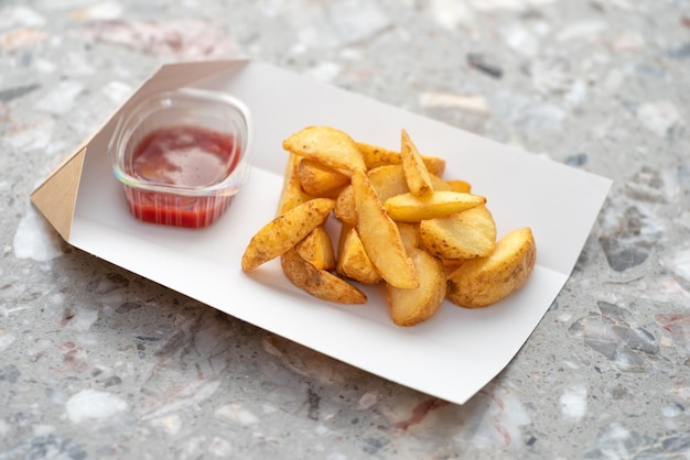 Fried potato wedges in kraft paper basket takeaway food concept